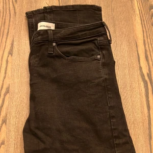 Svarta jeans från Jack & Jones - Snygga svarta jeans från Jack & Jones med klassisk femficksdesign och raka bakfickor. Jeansen har en stilren look och är tillverkade i ett mjukt denimtyg som ger en bekväm känsla. Perfekta för dig som gillar en enkel och tidlös stil.