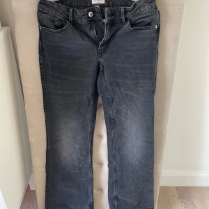Gråa bootcut jeans från Lindex - Snygga gråa jeans från Lindex med klassisk femficksdesign och raka ben. Jeansen har normal midja och subtila slitningar framtill för en cool look. Perfekta till sneakers eller boots och passar till många olika stilar. Slitna längst ner💞