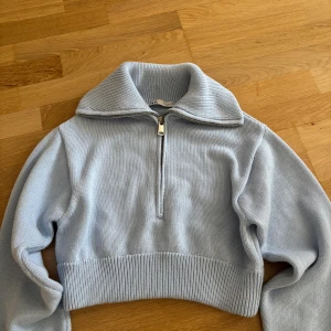 Ljusblå stickad half zip från Zara - Superfin ljusblå stickad tröja från Zara med hög krage och half zip-dragkedja. Tröjan har bred ribbad mudd nedtill och vid ärmslut, vilket ger en snygg och modern look. Ordinarie pris: 450kr