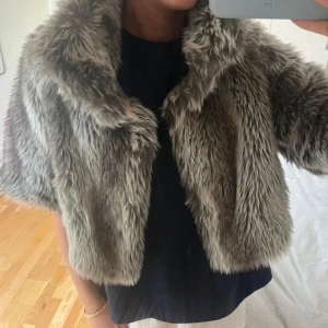Grå pälsjacka från Lipsy London - Supermjuk och fluffig grå pälsjacka från Lipsy London. Jackan har kort modell, bred krage och är tillverkad i syntetiskt pälsmaterial. Mycket bra skick! 