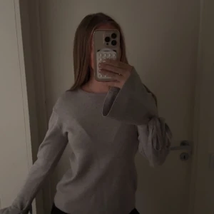 Grå stickad tröja med knytärmar - Superfin ljusgrå stickad tröja med vida ärmar och snygga knytband vid handlederna. Skriv om ni har några frågor. 