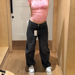 Svarta wide jeans från BDG urban outfutters - Säljer ett par svarta jeans från BDG med bred passform och raka ben. Jeansen har låg midja, stora bakfickor och en snygg spänndetalj bak i midjan. Tillverkade i klassisk denim med en något tvättad look. Perfekta för en avslappnad och trendig stil.