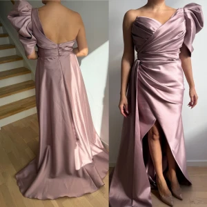 Ljuslila långklänning med slits - Säljer en elegant ljuslila långklänning i glansigt satinmaterial. Klänningen har en axel, stor volangdetalj på axeln och omlottliv med drapering. Slits framtill ger en snygg touch och kjolen faller vackert mot golvet. Perfekt för dig som vill sticka ut. Endast använt en gång på ett bröllop, original pris 5500kr