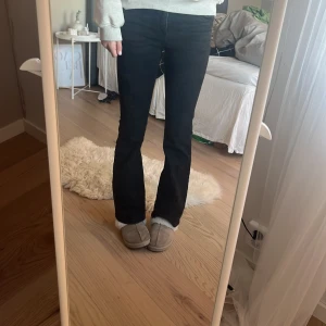 Svarta bootcut jeans - Säljer ett par svarta jeans med bootcut-modell och hög midja. Jeansen har klassiska bakfickor och sitter tajt över låren innan de släpper ut vid bensluten. Perfekta för dig som gillar en tidlös och snygg siluett.