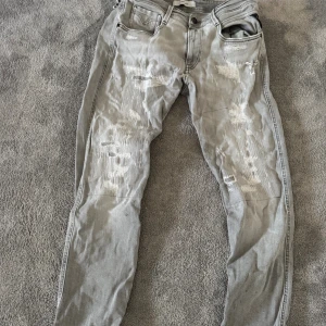 Replay jeans Anbass  - Säljer ett par grå jeans från Replay med coola slitningar och lagade detaljer framtill. Jeansen har klassisk femficksdesign, skick 9/10 nypris:3300 