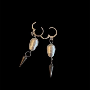 Silvriga örhängen med pärlor och spikes - Unika örhängen i silverfärg med oregelbundna vita pärlor och coola metallspikar som hänger ned. Ger en edgy vibe med mixen av klassiska pärlor och moderna detaljer. Perfekta för dig som vill sticka ut med din stil.OBS, Endast öronhångena på första bilden i andra bilden visar det i perspektiv till våra andra smycken💕