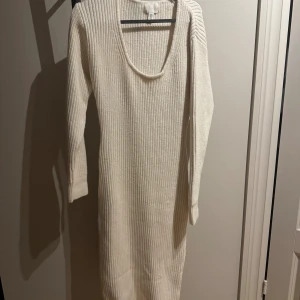 Vit ribbad stickad långklänning - Supermysig vit stickad långklänning från H&M med ribbad struktur och lång ärm. Klänningen har en djup rundad ringning och är perfekt för kyligare dagar. Enkel och stilren design som är lätt att matcha med boots eller sneakers.
