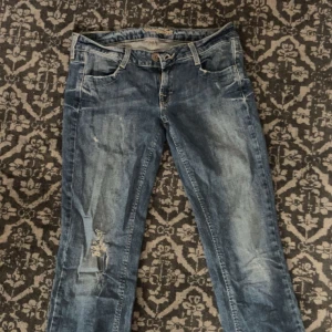 Lågmidjade vintage jeans - Dessa jeans är lågmidjade och utsvängda, med en cool design av silvriga stenar på bakfickorna. 
