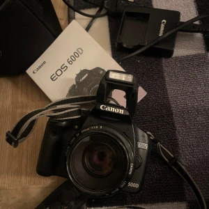 Canon EOS 500D - Canon EOS 500D systemkamera med Canon EF 50mm f/1.8 II-objektiv. Inkluderar laddare, batteri, SD-kort, kameraväska och manual. Kameran är i gott skick med synligt fungerande display och blixt. Perfekt för både nybörjare och entusiaster.