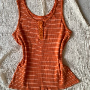 Topp med söta knappar!💋 - En sjukt fin orange topp med vita ränder och blommiga knappar framtill. Ett statementplagg utan dess like mina vänner. Köpte i syfte att sy om den men det hände aldrig haha💋