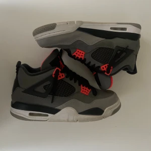 Jordan 4 Retro Infrared - Säljer ett par Nike Air Jordan 4 Retro i Infrared colorway. Skorna har klassisk mesh på sidorna, svarta snören och den ikoniska Jumpman-loggan på plösen. Sulan är vit med svarta och grå partier. Perfekta för dig som gillar streetwear och sneakers med attityd.