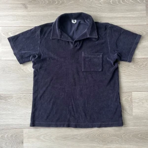 Mörkblå frotté t-shirt med krage - Snygg mörkblå t-shirt i frottématerial med klassisk krage och en bröstficka. Kortärmad och med en loose passform som ger en chill vibe. Perfekt för dig som gillar mjuka material.