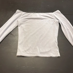Ljusblå offshoulder långärmad topp - Säljer en stilren ljusblå offshoulder topp med långa ärmar. Toppen har en enkel och clean design utan mönster eller detaljer, perfekt för att matcha med olika outfits. Mjuk och skön känsla i materialet.