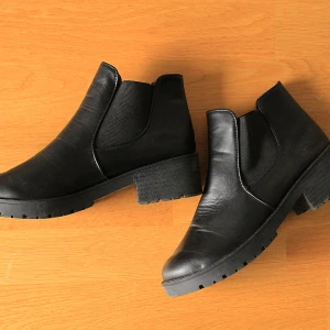 Svarta chelsea boots - Svarta chelsea boots i skinnimitation med låg klack och rund tå. Perfekta för dig som vill ha en stilren och klassisk look. Använda ett fåtal gånger.