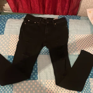 Svarta skinny jeans Jack & Jones - Svarta skinny jeans från Jack & Jones, modell Liam. Jeansen har en tight passform och klassisk femficksdesign. Tillverkade i stretchigt jeansmaterial för extra komfort. Perfekta för dig som gillar en smal siluett och stilren look.