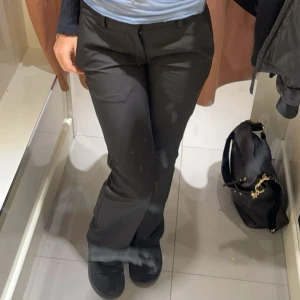 Svarta kostymbyxor - Snygga svarta kostymbyxor med bootcut-snitt och klassisk passform. Byxorna har hällor för bälte, diskreta fickor och stängs med knapp och dragkedja. Perfekta för en stilren och trendig look.