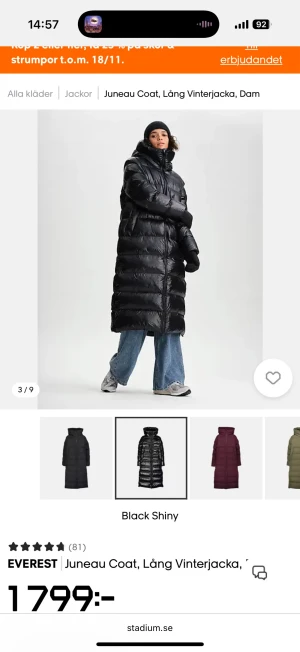 Svart lång pufferjacka från Everest - Lång, glansig svart pufferjacka från Everest med hög krage och huva. Jackan har quiltad design, dragkedja hela vägen och breda kanaler. Perfekt för kalla vinterdagar och riktigt snygg till streetwear-stil.