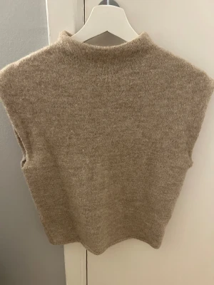Beige stickad tröja från Gina Tricot - Säljer en beige stickad tröja från Gina Tricot i mjuk ullblandning. Tröjan har en enkel, rak passform och hög hals. 