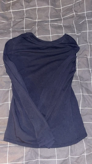 Mörkblå långärmad tröja i bomull - En enkel och stilren mörkblå långärmad tröja i mjuk bomull. Tröjan har rund halsringning och en normal passform som funkar till många olika outfits. Perfekt för dig som gillar basic och bekvämt.