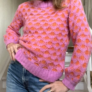 Tunn stickad tröja i klara färger - Löst stickad tröja från kvalitetsmärket InWear. Tröjans design med snyggt hålmönster i chockrosa/lila/orange matchar namnet  -  Honey Pullover. Modellen på bilden har strl 36/S. Plagget är XS. Våga välja färg!