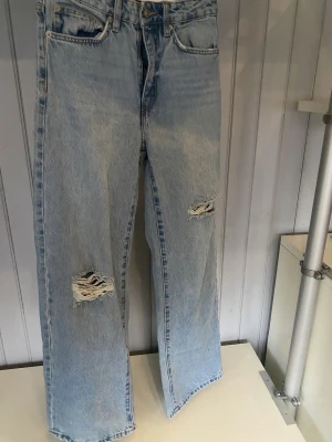 Ljusblå ripped jeans från 157 - Snygga ljusblå jeans från 157 med breda raka ben och slitna detaljer på båda knäna. Storlek 36. Aldrig använda 