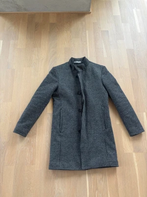 Dressad Jack från  Zara i toppskick  - Snygg rutig dressad jacka från Zara i svart och grått. Toppskick, sparsamt använd. Dragkedja och knäppning framtill. Yttermaterial i ullmix och quiltat foder för extra värme. Diskreta fickor på sidorna. Perfekt för höst och vinter.storlek S. Nypriset var 1500 kr.