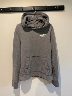 Grå hoodie från Hollister med huva - Snygg Hollister-tröja i storlek Medium! Hoodien är både bekväm och stilren, perfekt för avslappnade eller bara till vardags. Tröjan är i bra skick och har  Hollisters klassiska logga. Priset är inte helt spikat och kan justeras vid snabb och smidigt köp. Tveka inte på att skriva vid frågor😁