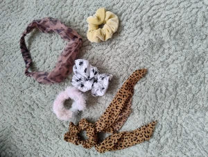 5-pack scrunchies och hårband mix - Säljer ett set med fem håraccessoarer: ett beunt hårband med leopard-mönster, en gul scrunchie i sammet, en vit scrunchie med svarta spindlar, en fluffig scrunchie i ljusrosa och blått samt en leopardmönstrad scrunchie med rosettband. Perfekt för att ge din frisyr extra attityd.
