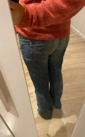 Blå bootcut jeand - Säljer ett par blå jeans, lågmidjade bootcut. De är utsedda längst ner. Jeansen har supersnygga fickor bak med dekorativa sömmar och är i ett mjukt denimtyg. Färgen är mellanmörk blå med lätt slitning för en cool vibe. Innerbenslängd: 77cm, midjemått: 38cm