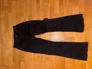 Svarta bootcut jeans - Säljer ett par svarta jeans med bootcut passform. Byxorna har klassisk femficksdesign och är tillverkade i ett mjukt jeansmaterial. Perfekt för dig som gillar en lite vidare siluett nedtill och vill ha en stilren look.
