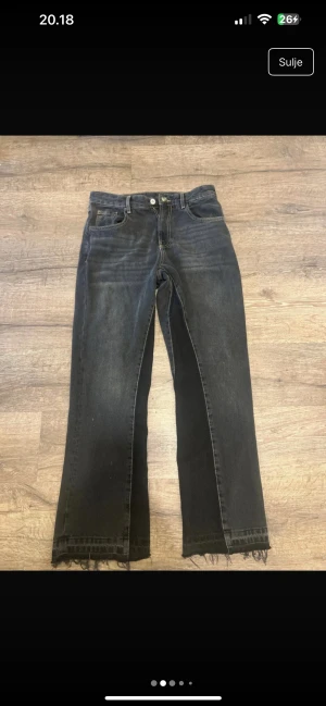 Svarta raka jeans från Zara - Svarta jeans från Zara med raka ben och råa, fransiga benslut. Jeansen har klassisk femficksdesign och subtila slitningar för en avslappnad look. Tillverkade i denim med en mörk tvätt som ger en cool vibe.