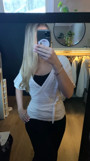 Vit omlottopp med knyt - Säljer en fräsch vit omlottopp med knyt i midjan och korta ärmar. Toppen har en v-ringad design. 🤍