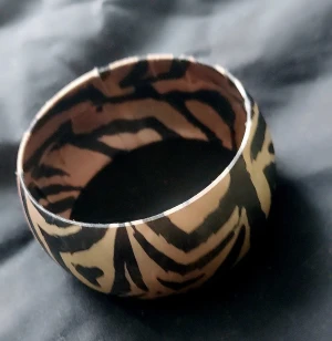 Brett armband med zebramönster - Coolt brett armband med svart och beige zebramönster. Armbandet har en rund form och är tillverkat i ett lätt material, perfekt för att ge din outfit en edgy touch. Mönstret är tydligt och ger en trendig känsla.