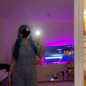 Ljusblå jeans jumpsuit med dragkedja - Säljer en snygg ljusblå jeans jumpsuit med kort ärm och markerad midja. Jumpsuiten har en lång dragkedja framtill, klassisk krage och fickor på sidorna. Perfekt för dig som gillar en cool och trendig denimlook.