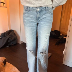 Ljusblå ripped jeans från Gina Tricot - Säljer dessa ljusblå low lose jeans från Gina Tricot med snygga slitningar på benen och broderad bakficka. Jeansen har normal passform och perfekta för en avslappnad och trendig look, jeansen är knappt använda och är i jätte bra skick🩵