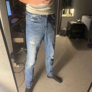   jeans från Levi's - Säljer ett par blå jeans från Levi's med snygga slitningar och lätt tvättad look. Modellen har klassisk femficksdesign, raka ben och normal passform. Perfekt för dig som gillar en avslappnad och trendig stil.