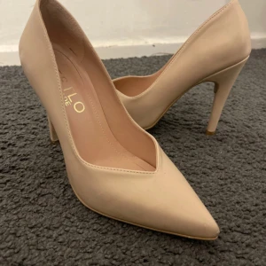Beige pumps med spetsig tå - Stilrena pumps i beige med spetsig tå och hög klack. Skorna har en klassisk form och är tillverkade i ett slätt material som ger en elegant look. Perfekta för dig som gillar en enkel men snygg stil.