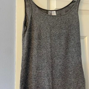 Grå ärmlös linnetopp från H&M Divided - Säljer en enkel och stilren grå linnetopp från H&M Divided i storlek XS. Toppen är ärmlös med rundad halsringning och har en mjuk, stretchig känsla. Perfekt att matcha med jeans eller shorts för en chill look.