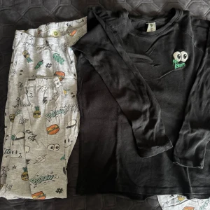 Svart långärmad pyjamas Lindex 134/140 - Svart långärmad tröja från Lindex med coolt broderat ögonmotiv och texten 'No Rules' i vitt och grönt på bröstet. Tillverkad i mjuk bomull, perfekt för dig som gillar enkel stil med en twist. Passar dig som vill ha en chill och bekväm look.