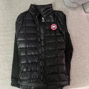 Svart dunväst från Canada Goose - Svart quiltad dunväst från Canada Goose med klassisk logotyp på bröstet.  Äkta. Pris kan sänkas vid snabbaffär