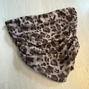 Leopardmönstrad croppedtop  - Säljer en snygg topp med leopardmönster i bruna och beige toner. Toppen har sömmar i sidorna för att framhäva siluetten samt en kant upptill som kan hjälpa att hålla toppen uppe hela kvällen! Aldrig använd och i topp skick! 