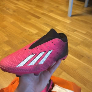 Adidas X Speedflow+ FG  + Träningskonor  - Säljer mina Adidas X Speedflow+ FG.  storlek 43⅓! Använda några få gånger – i riktigt bra skick. Lätta, bekväma på planen,  Sko snören ingår ej men passar bekvämt ändå. Går och köpa billigt i affär. Passar dig som vill ha en skön upplevelse på fart och kontroll! På köpet får du 30 träningskoner i fint skick, Perfekt paket för både träning och match! Vid snabb affär kan vi diskutera priset. 