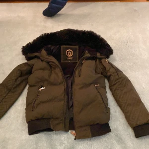 Grön pufferjacka Glorious Gangsta XS - Säljer en grön pufferjacka från Glorious Gangsta i storlek XS. Jackan har en fluffig huva med pälsdetalj, flera dragkedjefickor och ribbade muddar. Märket syns tydligt på ärmen och insidan. Perfekt för dig som gillar streetwear och vill ha en varm jacka med coola detaljer.