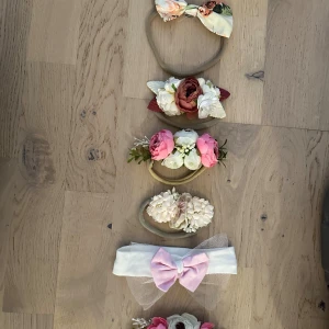 Söta blommiga diadem och hårband  - Fem superfina diadem och hårband för baby, med blommor i rosa, vitt och beige samt rosetter. Ett hårband har en ljusrosa prickig rosett och tyll, de andra har blommor i olika färger och former. Perfekt för att ge en gullig touch till din look.Sött pannbandsset för bebis 0-3 månaderEtt set med sex söta pannband för bebisar i åldern 0-3 månader. Pannbanden har olika blommor och rosetter i olika färger och stilar. Pannband håraccessoar 