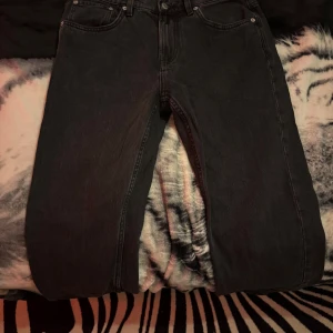 Svarta jeans från 157 New Classic - Svarta jeans från 157 New Classic med klassisk femficksdesign och raka ben. Jeansen har en enkel look utan synliga mönster eller slitningar, och är tillverkade i ett robust jeanstyg som passar perfekt till sneakers eller boots. Snyggt val för dig som gillar stilrena och tidlösa byxor. Storlek 30-32