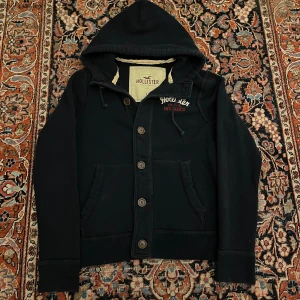 Vintage hollister cardigan/hoodie! - Riktigt fet vintage  Hollister cardigan/hoodie! Dessa har blivit extremt eftertraktade senaste så därav priset! Bra skick inga konstigheter!  Mått: Bredd: 52cm Längd: 64cm