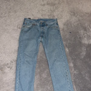 Levi's 501 ljusblå jeans W31 L30 - Säljer ett par klassiska Levi's 501 jeans i ljusblå tvätt. Modellen har rak passform, fem fickor och knappgylf. Jeansen har den ikoniska läderpatchen bak och röda Levi's-tag vid bakfickan. Perfekt för dig som gillar tidlös denimstil.