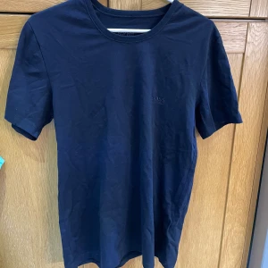 Mörkblå t-shirt från HUGO BOSS - Snygg mörkblå t-shirt från HUGO BOSS med diskret broderad logga på bröstet. Klassisk rund halsringning och korta ärmar. Tillverkad i mjuk bomull för en skön känsla och stilren look.