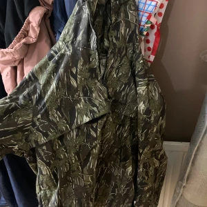 Camouflage vindjacka från Carhartt - Säljer en grön och brun camouflage vindjacka från Carhartt. Jackan är tillverkad i 100% nylon, har dragkedja framtill och praktiska fickor. Perfekt för dig som vill ha en streetig och funktionell look med snyggt mönster.