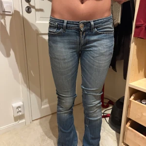 Replay blå bootcut jeans med dragkedjor - Snygga blå jeans från Replay med bootcut passform och låg midja. Jeansen har coola detaljer som dragkedjor på bakfickorna och en guldig Replay-plakett bak. Tillverkade i klassiskt denimtyg med lätt slitning för en avslappnad look. Säljer nu mina älskade replay jeans för jag vuxit ur dom!❤️väldigt  bra skick! Xs/s i storlek då dom är stretchiga 